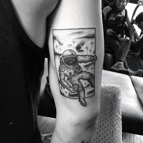Astronaut entering a doorway tattoo on guys outer arm