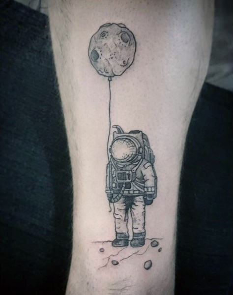 Astronaut with crater on a string tattoo on guy arm