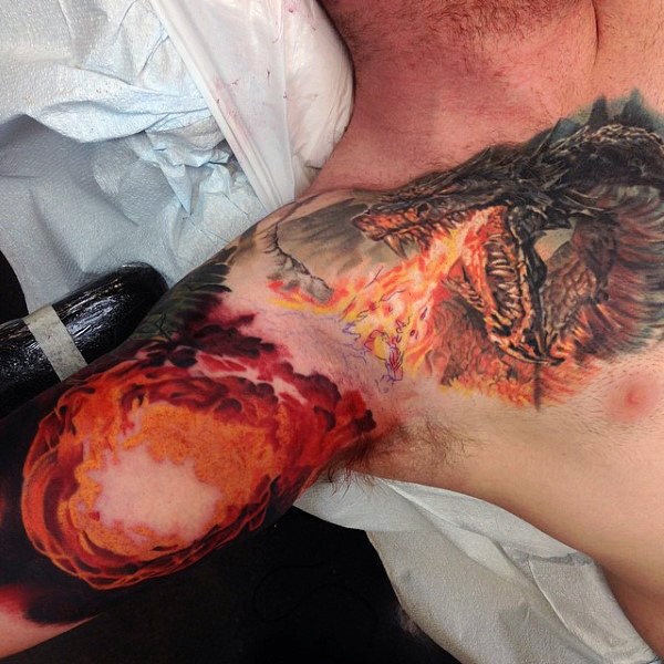 Dragon breathing fireball mens chest and inner arm tattoo