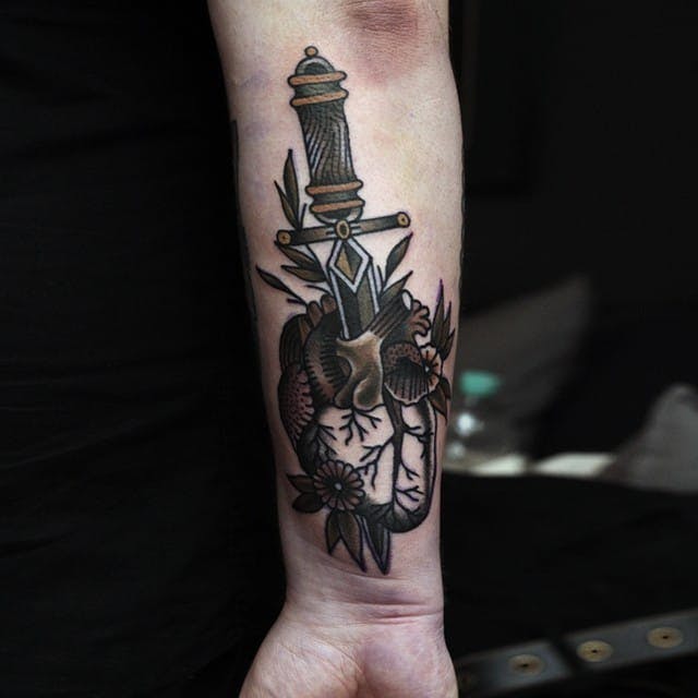 Forearm tattoo of a dagger through an anatomical heart