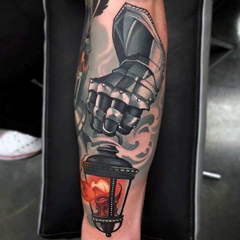 Knight gauntlet holding lantern on fire male leg tattoo