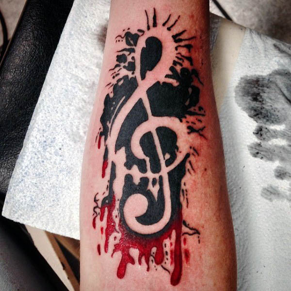 paint splatter negative space mens treble clef tattoo on forearm