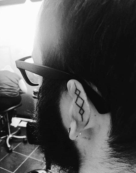 Man with tattoo of crossed lines on ear
