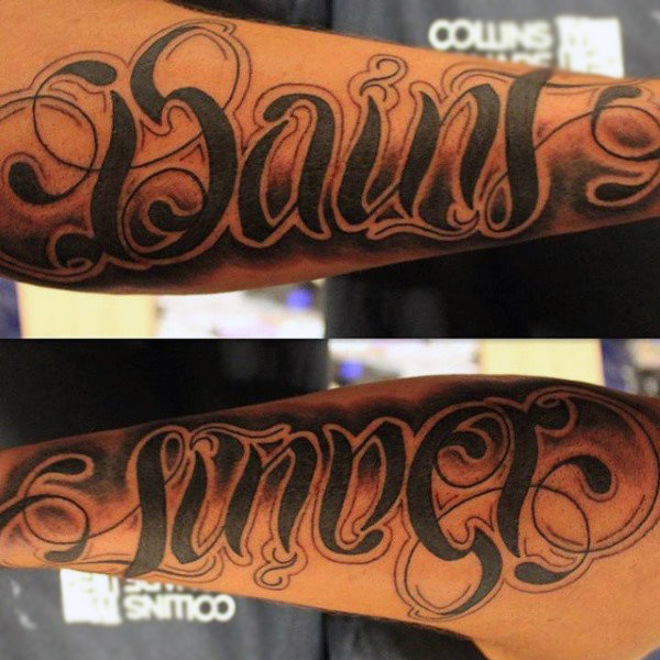 Man with saint sinner ambigram tattoo on arm