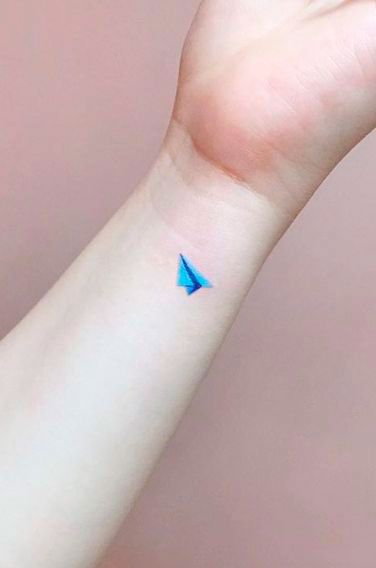 Tiny Paper Airplane tattoo on wrist