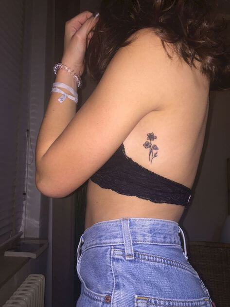 tiny flower tattoo on girl's rib