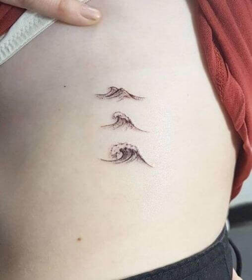 Tiny ocean waves tattoo on girl's rib