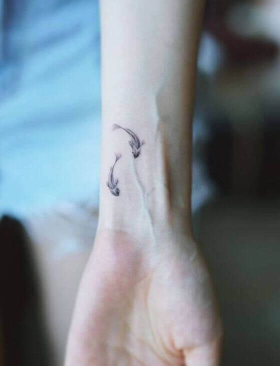 Cute Minimalist Fish tattoo on girl wrist