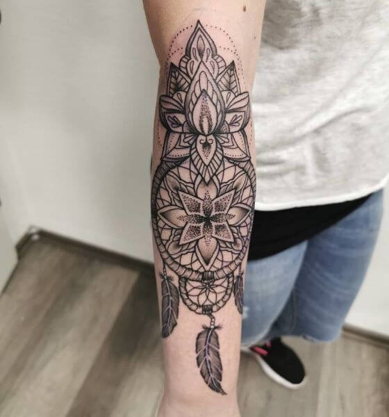 dream catcher tattoo with feather on forearm