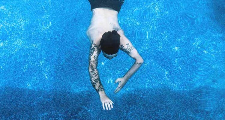 tattoo guy swim in a pool