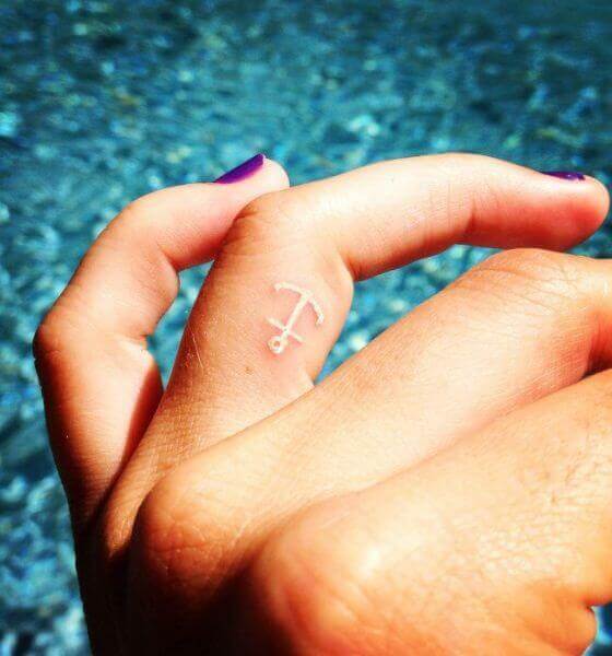 White ink anchor tattoo on finger