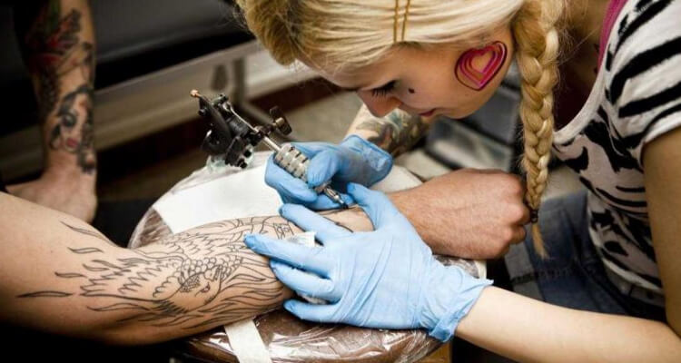 tattoo artist tattooing on arm
