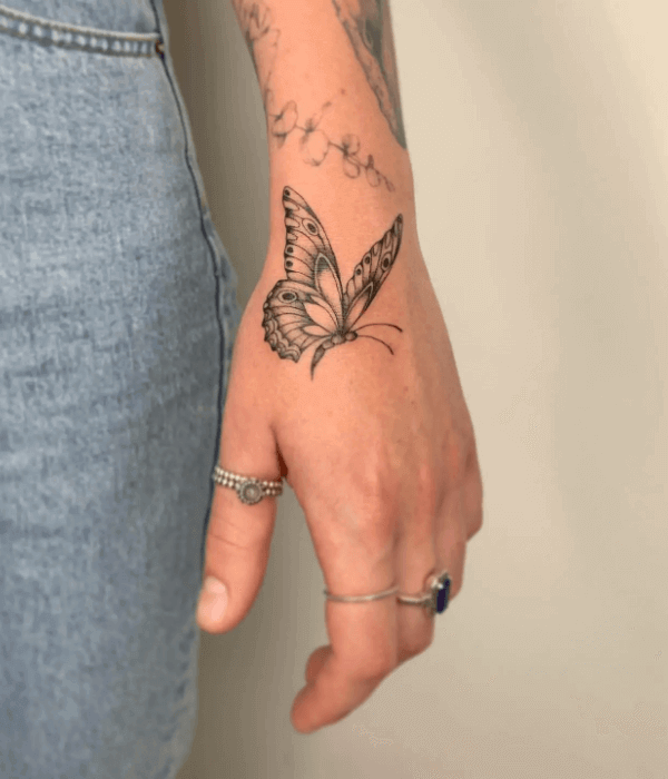 Fine line butterfly hand tattoo