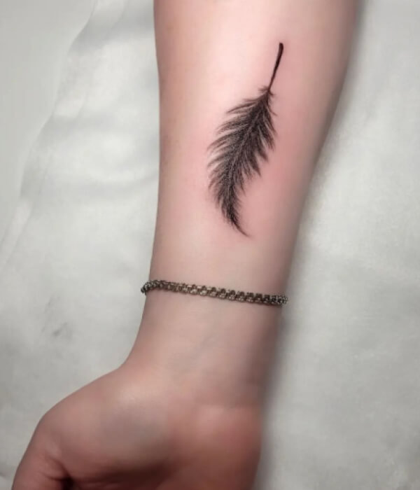 Black raven tattoo with a feather