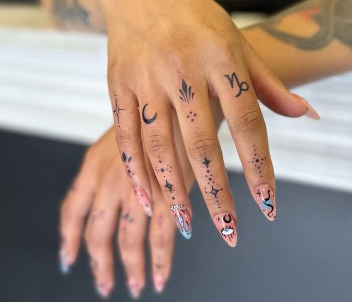 Finger Zodiac Tattoo 1 - Trending Tattoo Tiny zodiac and celestial finger tattoos featuring moons, stars, symbols, and fine-line dotwork on both hands.