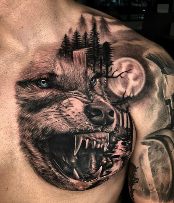 A realism-style black and grey chest tattoo featuring a snarling wolf with blue eyes, integrated with a pine forest, waterfall, and full moon landscape.