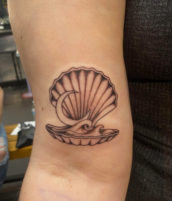 Black ink scallop shell tattoo with a crescent moon inside on the inner arm, featuring a symbolic and elegant seashell tattoo design.