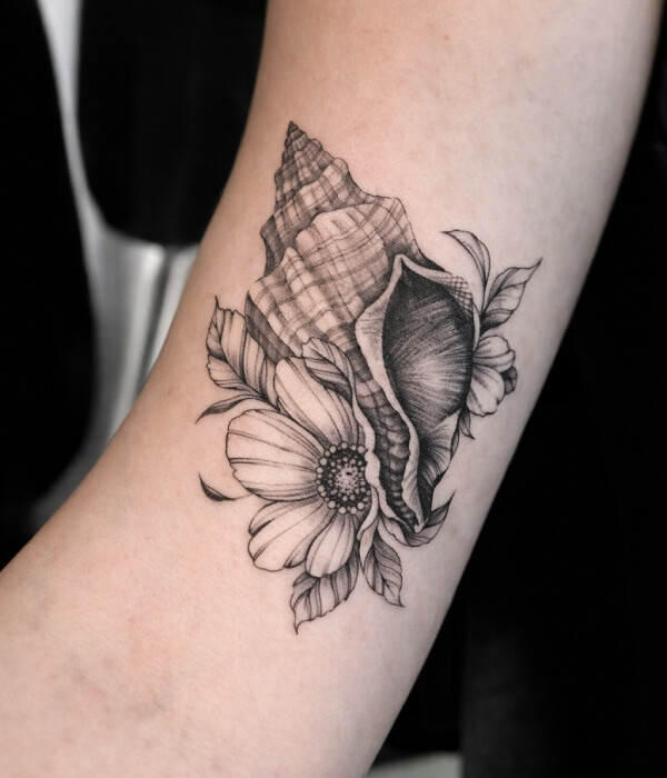 Black and grey seashell and flower tattoo on the inner forearm, featuring detailed conch shells with floral elements in a fine-line, realistic style.
