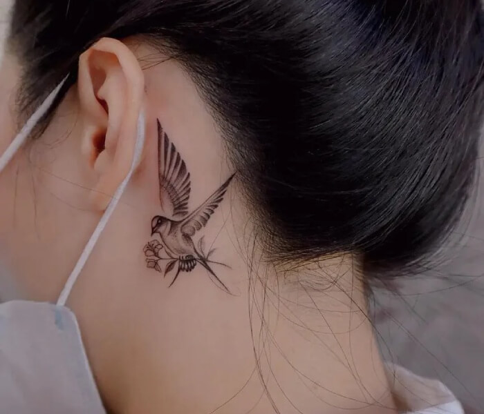 Tiny Tattoo Behind Ear - Trending Tattoo Tiny bird tattoo behind the ear featuring a delicate flying bird design in fine-line black ink.