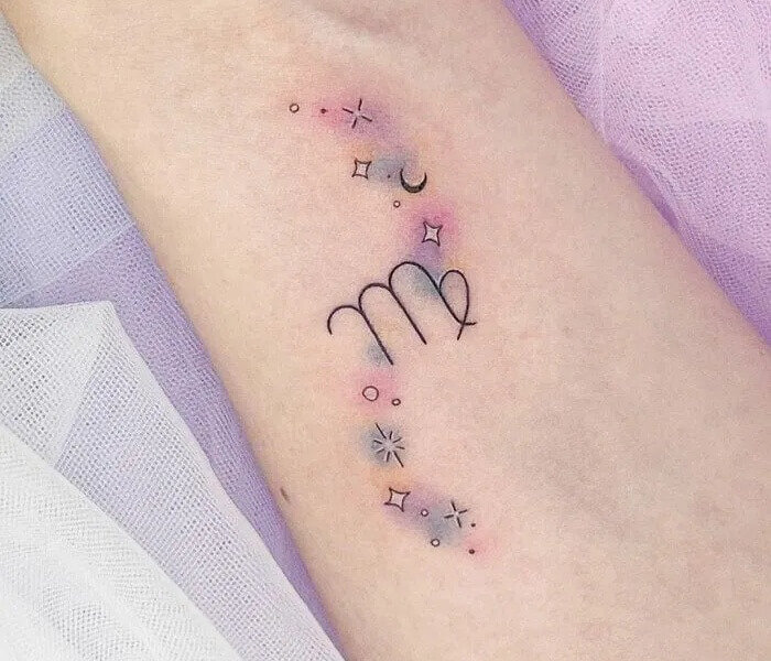 Tiny Watercolor Zodiac Tattoo - Trending Tattoo Tiny watercolor zodiac tattoo with minimalist line art, soft pastel shading, and small celestial symbols on the arm.