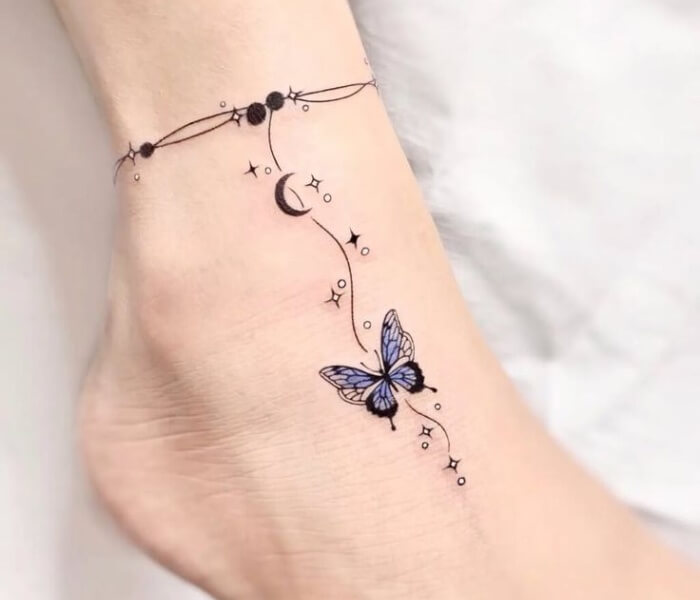 Tiny Zodiac Anklet Tattoo - Trending Tattoo Tiny zodiac anklet tattoo featuring a delicate butterfly, crescent moon, stars, and fine-line chain design around the ankle.