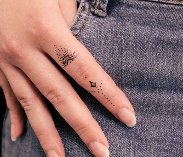 Zodiac Initial Tattoo 1 - Trending Tattoo Tiny zodiac initial tattoo on the finger featuring minimalist celestial symbols and fine-line dotwork details.