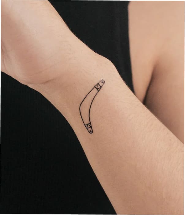 Minimalist fine-line bracelet-style tattoo on the inner wrist, featuring a delicate curved band with small geometric details at each end.