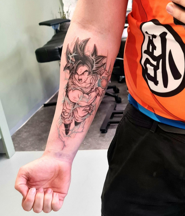 Black and grey tattoo of Goku from Dragon Ball Z on a forearm, featuring blue lightning effects and dynamic shading.
