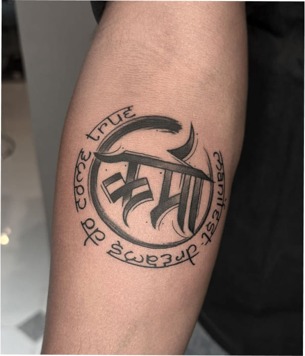 Circular forearm tattoo featuring stylized Devanagari calligraphy with the phrase “to love true is fearless,” designed in a bold black ink circle.